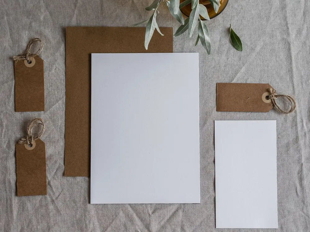 Kertas surat, amplop, dan label gantung di atas kain linen